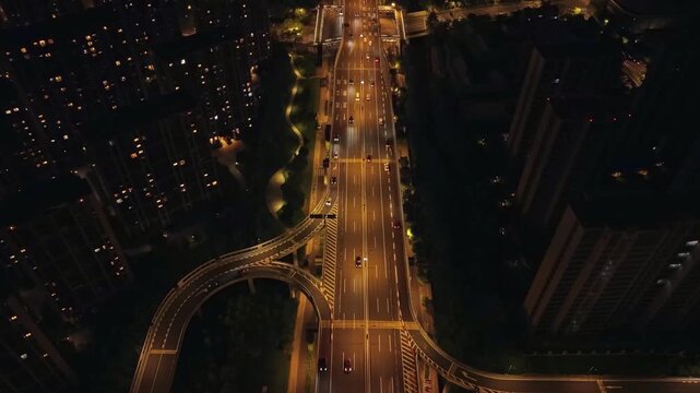 Aerial view of urban freeway interchange at night in Hangzhou city with car headlights showing traffic moving on the multiple roadways