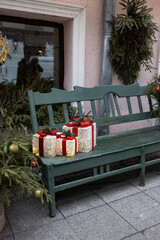 Decorative metal bench in front of a large Christmas tree decorated with red ornaments and...
