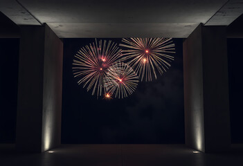 Fireworks display viewed from concrete architectural structure at nigh