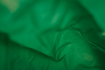 Extreme close up of green empty plastic bag background. The plastic surface is wrinkly and tattered...