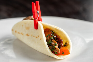 soft fajita tacos filled with meat, vegetables, and cilantro, held together with a red clothespin on a white background