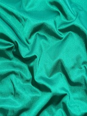 Fototapeta premium Smooth emerald green satin fabric with elegant folds and soft reflections, creating a luxurious and silky texture that shines beautifully under light, perfect for fashion, design, or interior inspirat