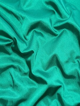 Smooth emerald green satin fabric with elegant folds and soft reflections, creating a luxurious and silky texture that shines beautifully under light, perfect for fashion, design, or interior inspirat