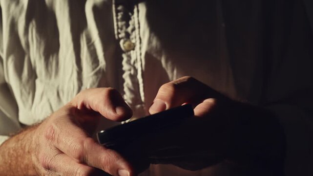 Male hands using smartphone for business communication in bright office interior, strong light and shadow emphasizing focus. 4K