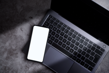 Phone screen mockup laying on laptop desktop.