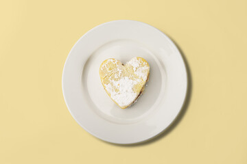 Heart shaped cookie lying on white plate on white background