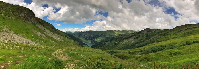 Panoramic view of a lush green mountain valley under cloudy skies