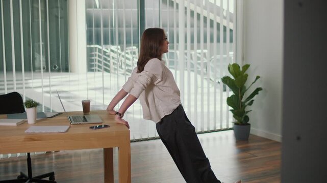 Employee Engagement. Female Worker Practices Desk Push Ups in Office, Promoting Healthy Workplace, Stress Relief, Wellness Routine, Positive Culture, Productivity Hacks, and Future of Work Balance
