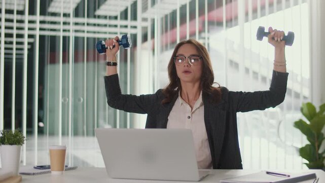 Office Ergonomics and Employee Wellbeing. Office Manager Performs Shoulder and Upper Spine Exercise with Dumbbells at Desk to Improve Posture, Prevent Pain, Support Productivity and Corporate Wellness