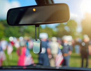 Car rearview mirror with military dog tag hanging, memorial event in background.
