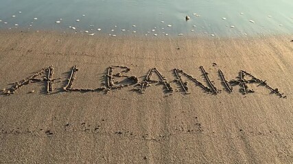 The word “ALBANIA” written on sandy beach near the shoreline