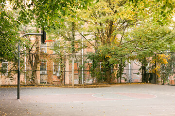 Quiet basketball court surrounded by colorful trees in an urban setting on a calm autumn day
