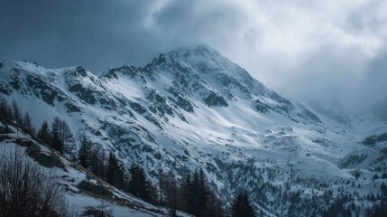 A vast landscape of snow-covered mountains rises under a moody sky filled with clouds. This remote setting showcases the beauty of winter in nature, untouched and serene.
