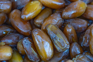 Sticky brown dates in a tight macro pile at a farmers’ market; selective focus reveals glossy texture for fresh produce storytelling and organic fruits lifestyle visuals.