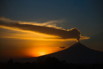 Stunning silhouette of Popocatépetl volcano erupting during a vibrant sunset. Fumarole and ash emerging under a dramatic sky in Mexico.
