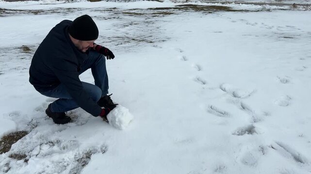 Laughter echoes through the winter park as a father and son bond over creating a lopsided snowman, followed by an energetic snowball battle.