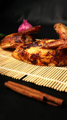 Roasted Chicken with Garlic and Cinnamon on Bamboo Mat in Dark Background