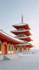 Naklejka premium Layered Orange Rooftops Of A Traditional East Asian Pagoda Temple Structure With Snow On The Ground And Clear Sky Above In Daylight