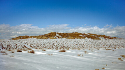 Naklejka premium Snow-Covered High Desert Landscape with a Barren Mesa and a Winding Path
