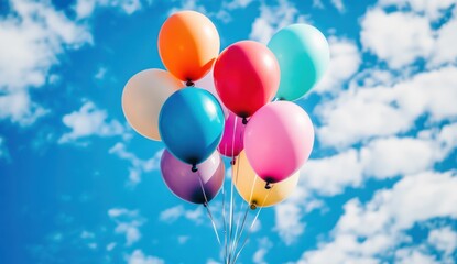 Colorful Balloons Floating Freely Against a Bright Blue Sky with Clouds