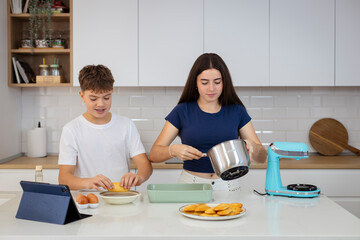 A teenage boy dipping biscuits in coffee and a teenage girl adding cream