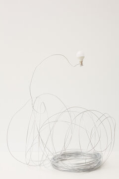Entangled stainless wire and LED bulb art installation against white background