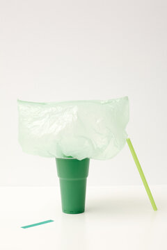 Emerald-green cup, light green straw and plastic bag with piece of tape