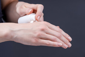 Applying hand cream for moisturizing and skincare, Close-up of woman&rsquo;s hands applying moisturizing cream from white dispenser bottle onto skin, focusing on personal care and hygiene.
