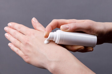 Applying hand cream for moisturizing and skincare, Close-up of woman’s hands applying moisturizing cream from white dispenser bottle onto skin, focusing on personal care and hygiene.