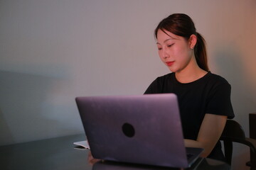 A woman is sitting at a table with a laptop in front of her