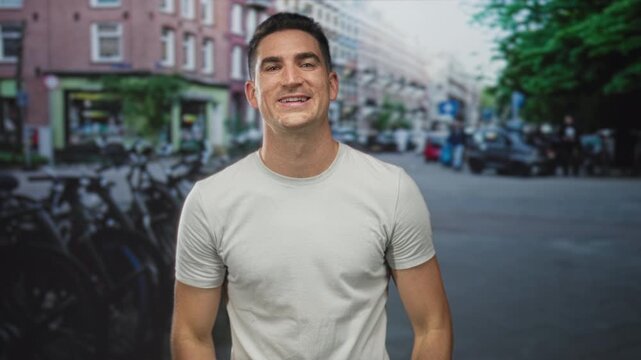 Young man presses cheeks with both hands on a busy city street, lips puckered and eyes wide; playful.