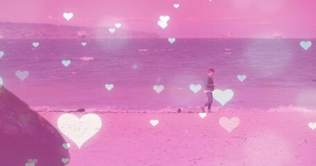 Walking man in jacket and jeans along sandy beach water's edge, with smartphone, copy space