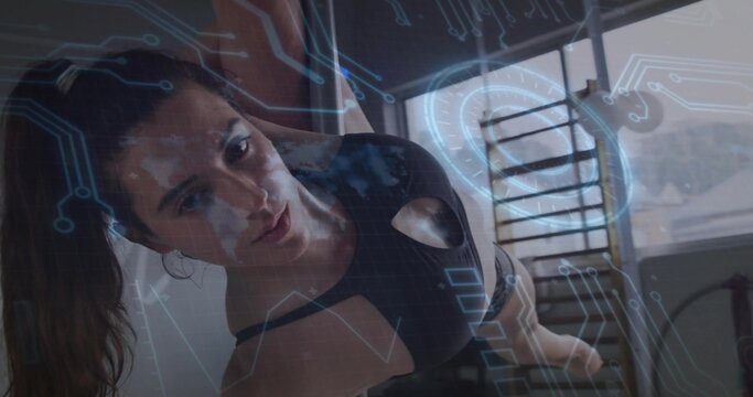 Woman in black sportswear holding side plank in workout room, with stall bars and digital overlay