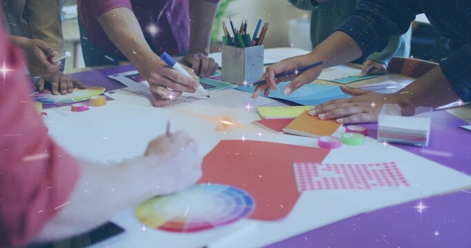 Collaborating team sketching and arranging at design studio, with paper cutouts and color wheel