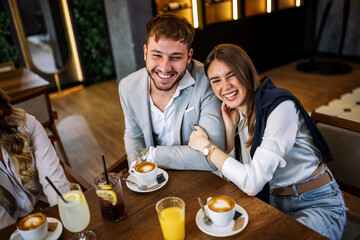 Couple hugging at restaurant with friends