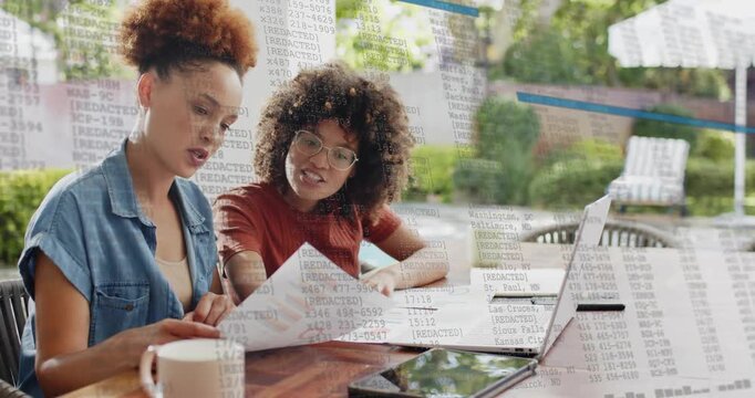 Two colleagues pointing to financial charts on patio, showing floating numerical data for insights