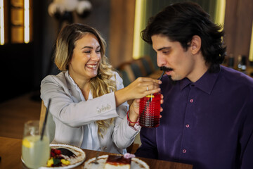 Girlfriend offering juice to boyfriend in cafe