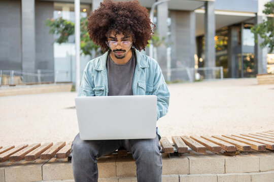 Man using laptop in urban setting outdoors
