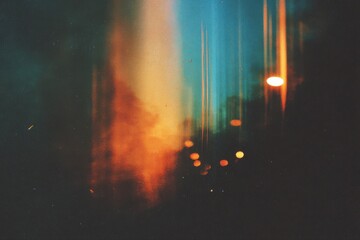 A blurry street light shining in the night with a vintage film grain effect, vertical light leaks, and subtle scratches.
