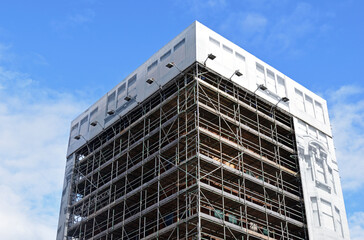 City Building Encased in Scaffolding seen from Below against Blue Sky © eyepals