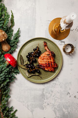 christmas still life Steak with fried grapes on a green plate, New Year's vibe candles, juniper and wooden New Year's toys, wooden mushrooms copy space