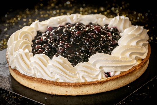 Delicious blueberry tart with whipped cream swirls on an elegant black background