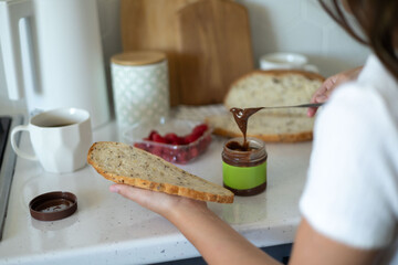 Preteen girl making a delicious breakfast with chocolate spread