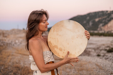 Hippie woman embracing nature with drum outdoors