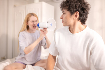 Playful woman using a megaphone to wake up her partner in the morning