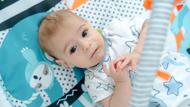 Baby on a colorful playmat with thoughtful expression