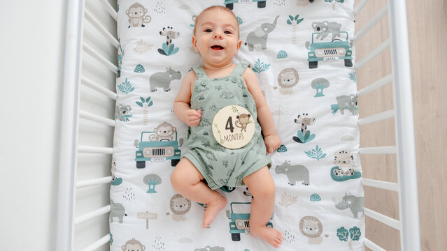 Adorable baby reaching four-month milestone in crib