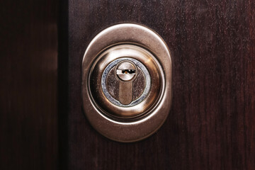 Metal door lock in wooden surface. Closeup of cylinder and keyhole. Concept of security and home...