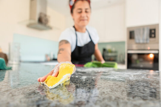 Woman cleaning kitchen countertop after baking bread
