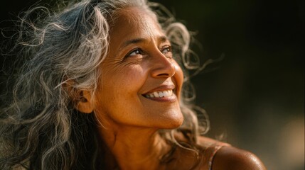 Joyful elderly woman with silver hair smiling brightly while looking up, radiating happiness and warmth in soft natural light capturing her inner beauty and serenity